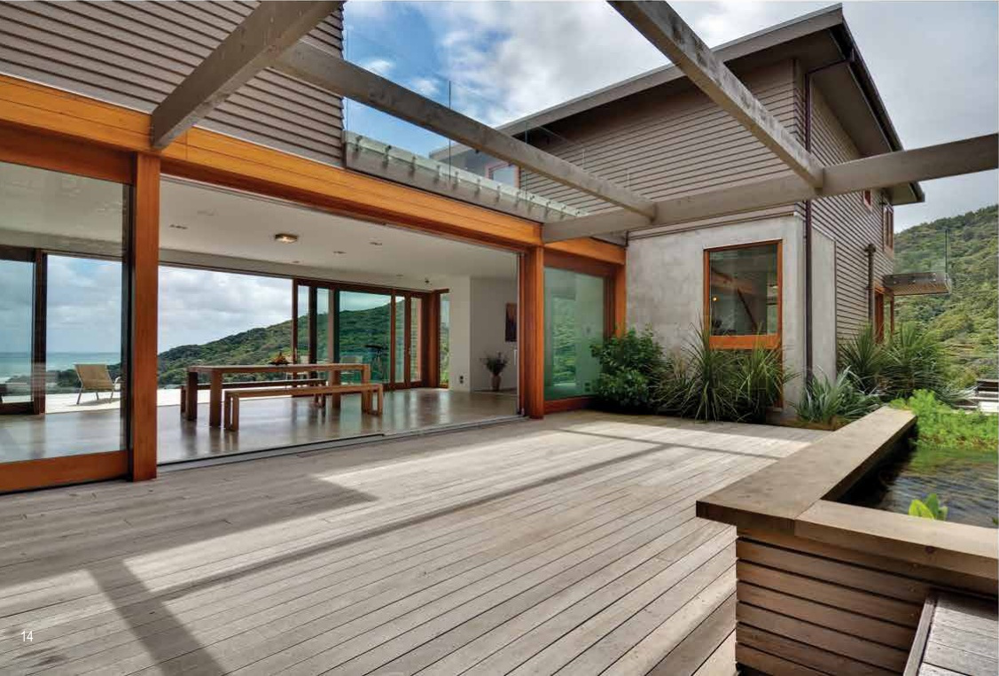 Wide lift-and-slide glazing opened onto a timber terrace with hills beyond